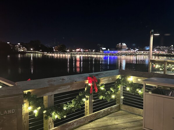Une terrasse en bois dotée d’une rambarde, décorée de guirlandes lumineuses et d’un nœud rouge.