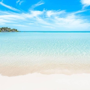 Una playa con agua turquesa cristalina y una orilla arenosa.