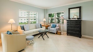 A living room with a sofa, armchair, coffee table, and a dresser. - Beachfront efficiency studio with 1 bath (Marco Island)