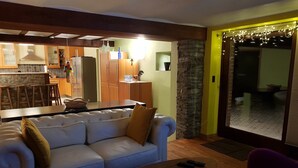 Un saló amb un sofà, una taula de centre i una zona menjador, amb una cuina al fons.