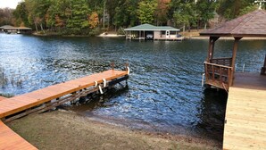Une jetée en bois s’avançant dans un lac, avec un belvédère et une maison en arrière-plan.