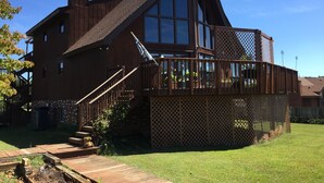 Une maison en bois à deux étages, dotée d’une grande terrasse et d’un escalier menant à l’étage supérieur.