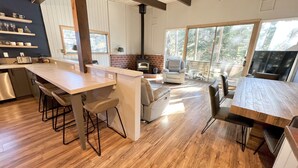 Una cocina moderna con una isla central, taburetes de bar y un comedor con una gran mesa de madera.