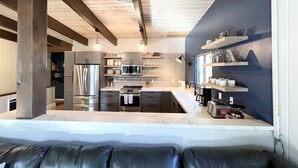 Una cocina moderna con electrodomésticos de acero inoxidable, vigas de madera y horno empotrado.
