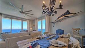 A dining area with a view of the ocean, a ceiling fan, and a chandelier. - Shores of Panama 1529-End Unit~Sleeps 8 (Panama City Beach)
