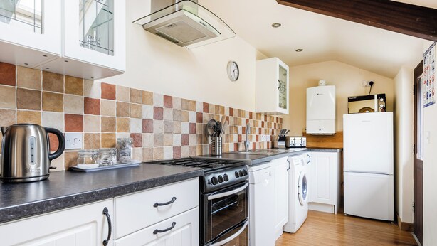 A compact kitchen with a gas stove, oven, and a built-in dishwasher. - The Shippon, Breathtaking Views, Private Hot Tub (Winkleigh)