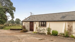 A single-story building with a sloped roof, a wooden door, and a window with a shutter. - The Shippon, Breathtaking Views, Private Hot Tub (Winkleigh)