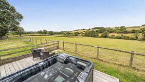 A hot tub on a wooden deck with a view of a grassy field and hills. - The Shippon, Breathtaking Views, Private Hot Tub (Winkleigh)