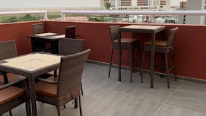 A rooftop terrace with a table and chairs, a view of the cityscape, and a railing. - Posh Hotel And Suites (Lagos)
