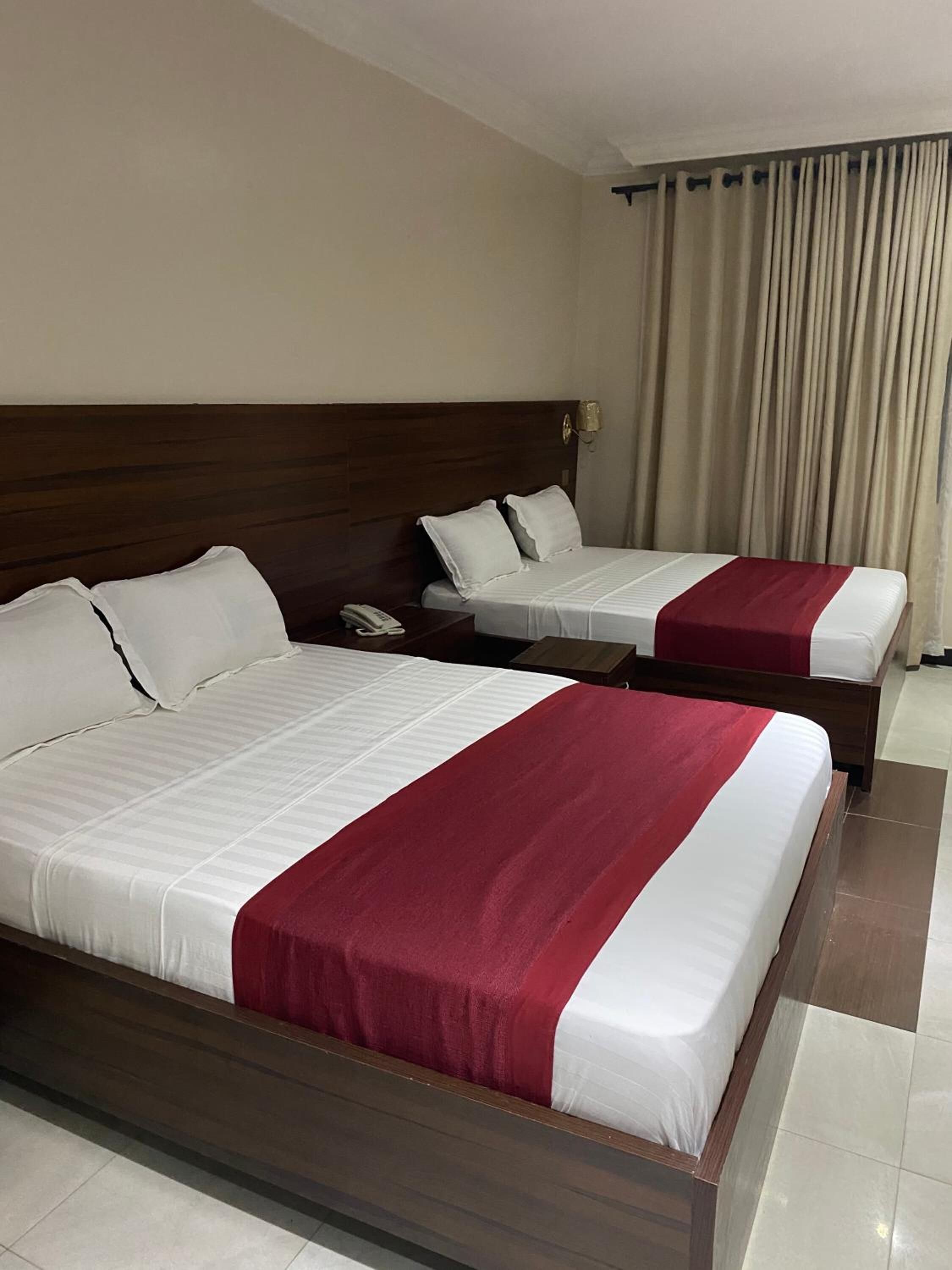 Une chambre d’hôtel avec deux lits, chacun agrémenté de draps blancs et d’un élément décoratif rouge.