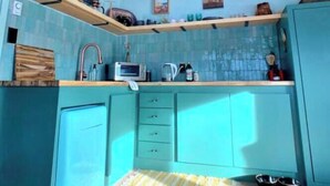 Una cocina con gabinetes color turquesa, vigas de madera y un tragaluz.