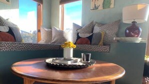 Una habitación acogedora con una mesa de madera, un banco con cojines y una ventana con persianas.