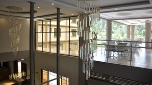 A spacious indoor area with large windows, a chandelier, and seating arrangements. - FK Resort & Spa (Marua)