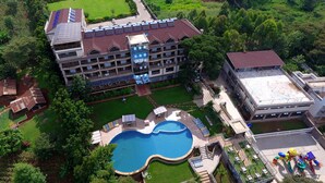 A multi-story hotel with a swimming pool, outdoor seating, and a tennis court. - FK Resort & Spa (Marua)