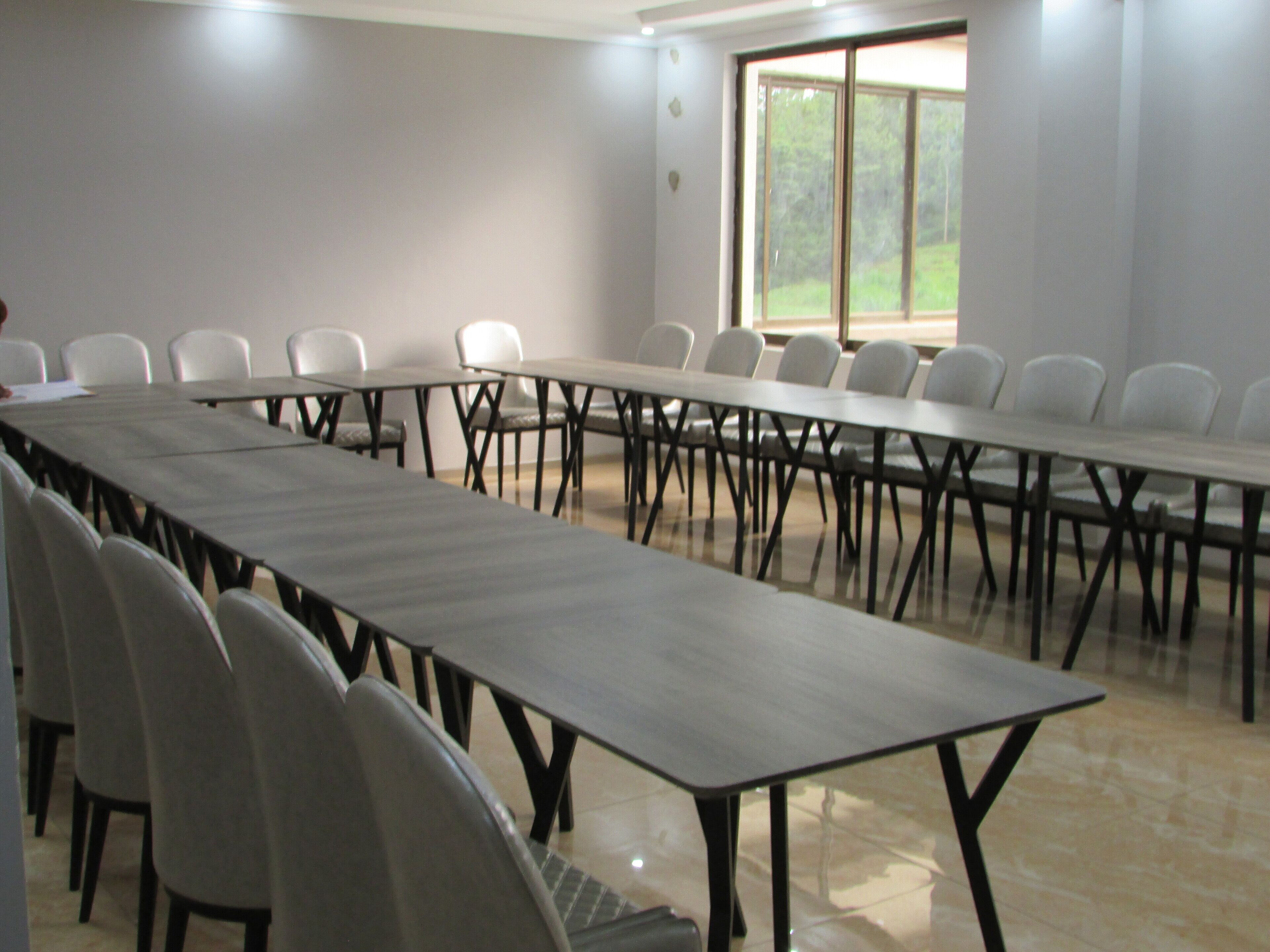 A conference room with a long table and chairs, large windows, and a tiled floor.