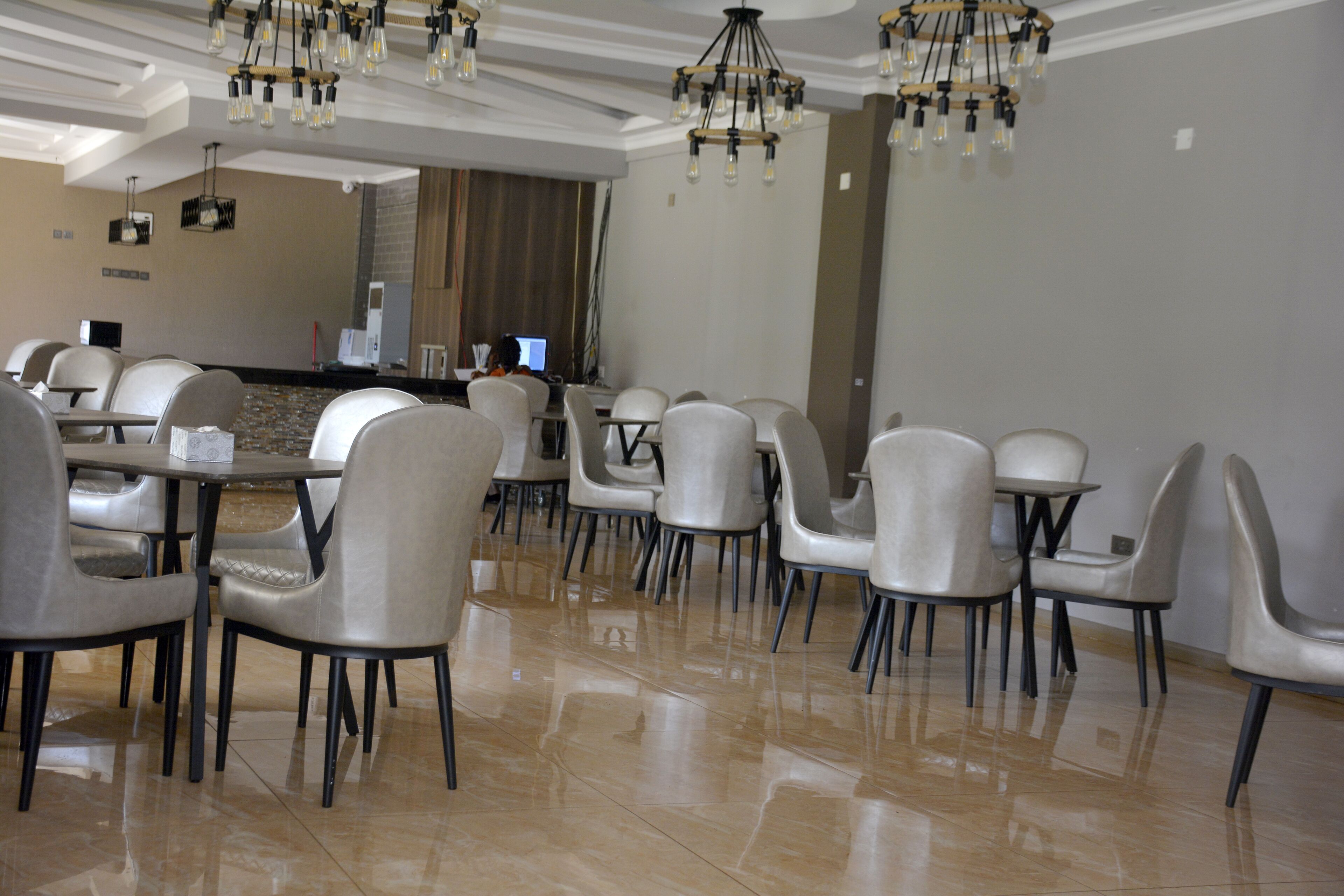 A modern dining area with a polished tile floor, contemporary chairs, and a central counter with a computer.