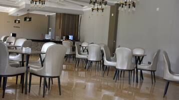 A modern dining area with a polished tile floor, contemporary chairs, and a central counter with a computer.