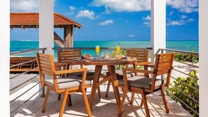 Una mesa y sillas de madera en un balcón con vista al océano.