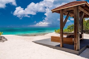 A wooden beach structure with a roof, situated on a sandy beach with clear turquoise water and a blue sky. - Villa Beach Shack (Providenciales)