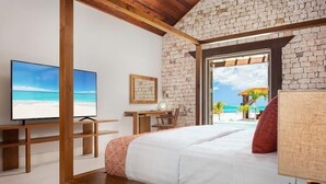 Un dormitorio con una cama grande, televisión, escritorio y vista al mar.