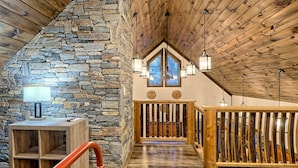 Un intérieur chaleureux avec un mur en pierre, un plafond en bois et une vue par la fenêtre.