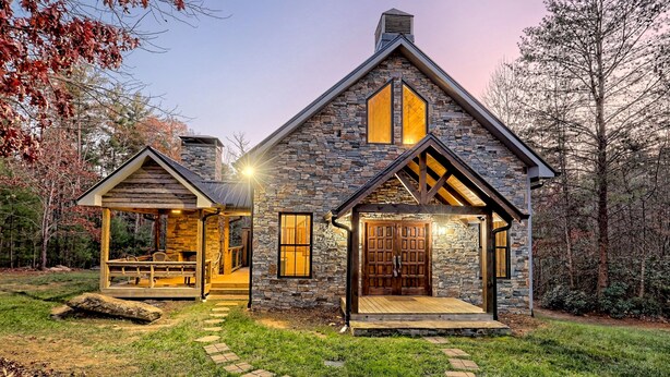 Une maison en pierre avec un porche en bois et une grande porte en bois.