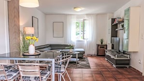 Un salon moderne avec une table à manger en verre, un canapé et un meuble pour la télévision.