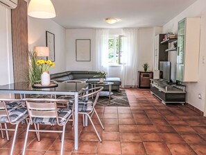 Een moderne woonkamer met een glazen eettafel, een bank en een tv-meubel.