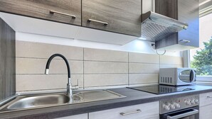 Une cuisine moderne équipée d’un évier en acier inoxydable, d’un four à micro-ondes et d’un four encastré.