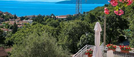 A balcony with outdoor furniture, a view of the sea, and a power line tower.