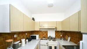 Uma cozinha compacta com armários brancos, micro-ondas, fogão e liquidificador.