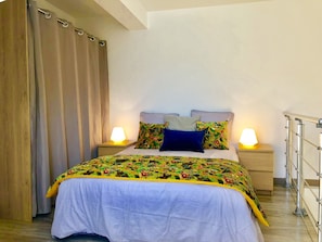 A bedroom with a bed, two bedside lamps, a wooden headboard, and a metal railing.