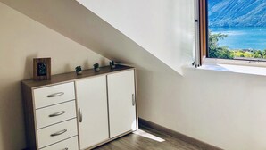 A room with a white cabinet, a framed picture, and a window overlooking a mountainous landscape.