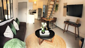 A modern living room with a sofa, coffee table, and a dining area with chairs and a table.