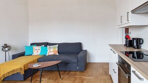 Un espace de vie compact comprenant un canapé, une table basse et un coin cuisine.