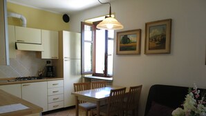 Cozinha compacta com área de refeições, sofá e janela com cortinas.