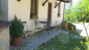 Um pátio com mesa e cadeiras, plantas em vasos e um pequeno jardim.