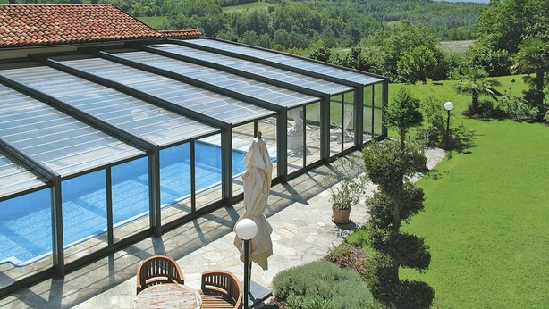 A glass-enclosed swimming pool with a patio area, surrounded by a lush garden and a view of rolling hills. - Wonderful  villa for 4 guests with WIFI, pool, TV, terrace and pets allowed (Cigliè)