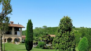 A two-story house with a tiled roof, surrounded by a well-maintained lawn and various trees. - Wonderful  villa for 4 guests with WIFI, pool, TV, terrace and pets allowed (Cigliè)