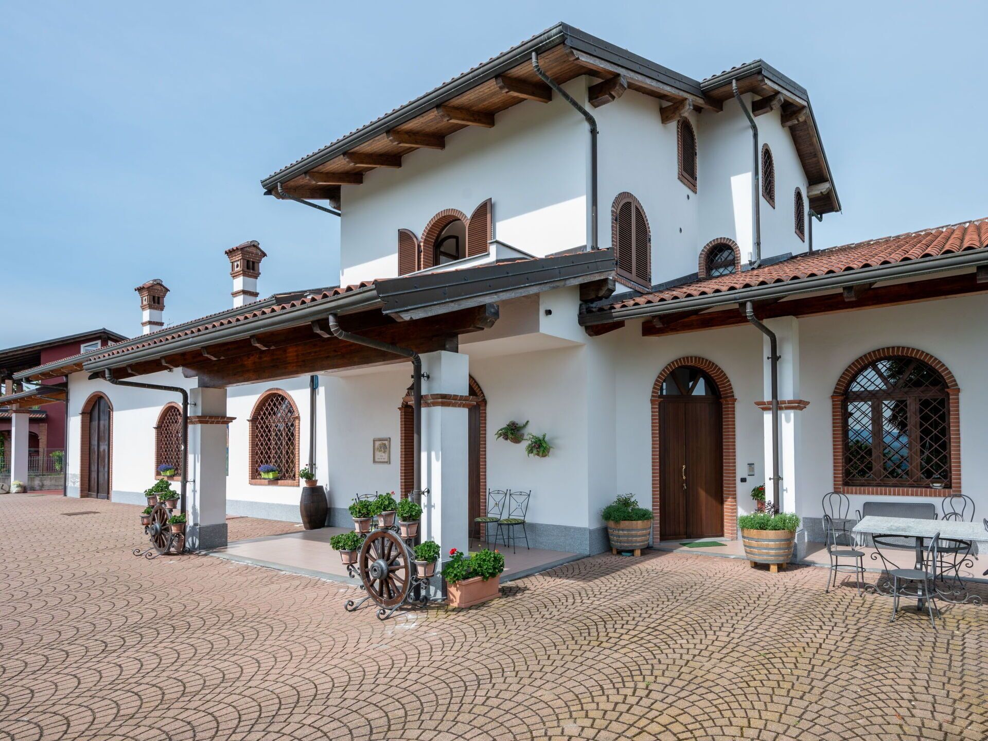 A two-story building with a white facade, multiple arched windows, and a tiled roof.