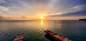 A wooden pier extending into calm waters at sunset.
