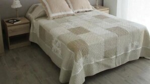 A bedroom with a bed, nightstands, a lamp, and a window with curtains. - Les Abris du Chateau (Mer)