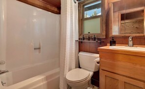 Une salle de bain avec une baignoire, des toilettes et un meuble-lavabo en bois.