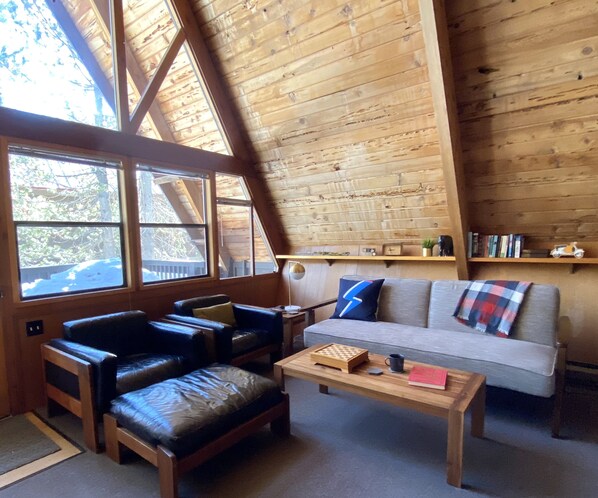 Une pièce chaleureuse avec un plafond en bois, un canapé, une causeuse et une table basse.