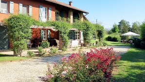 A rustic building with a brick facade, a covered patio area, and a gravel driveway. - Stunning private villa for 10 guests with WIFI, private pool, TV, terrace and pets allowed (Capriglio)
