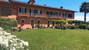 A two-story building with a balcony, a well-maintained lawn, and a variety of plants and flowers. - Stunning private villa for 14 guests with private pool, A/C, WIFI, TV, patio and panoramic view (Soglio)