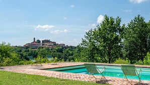 A swimming pool with two lounge chairs and a view of a hilltop town with buildings and a tower. - Stunning private villa for 14 guests with private pool, A/C, WIFI, TV, patio and panoramic view (Soglio)