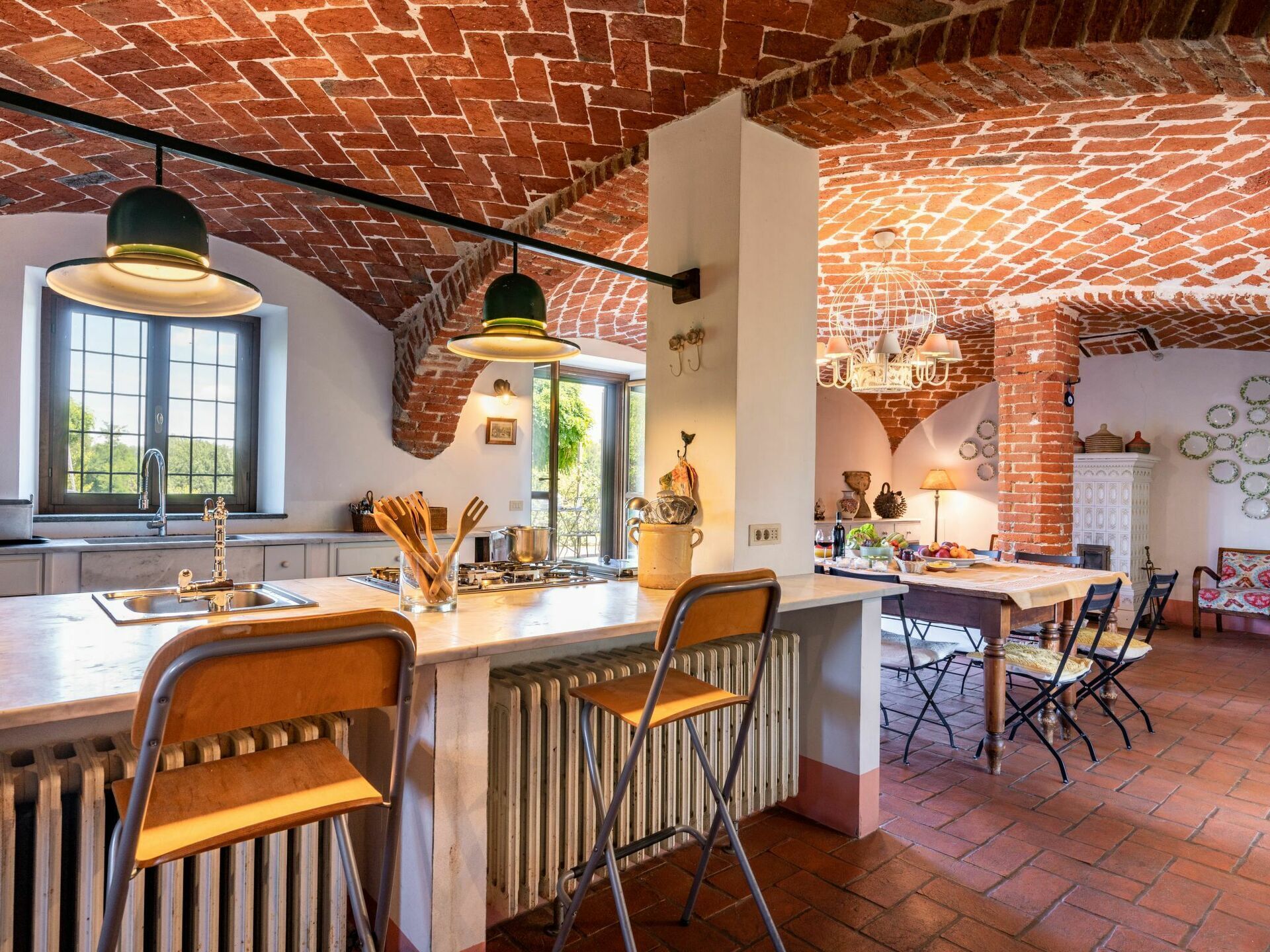 Una cocina con techo de ladrillo, una isla grande con taburetes de bar y un comedor con mesa y sillas.