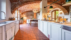 A kitchen with a brick arch ceiling, white cabinetry, and a central island with a stove. - Stunning private villa for 14 guests with private pool, A/C, WIFI, TV, patio and panoramic view (Soglio)