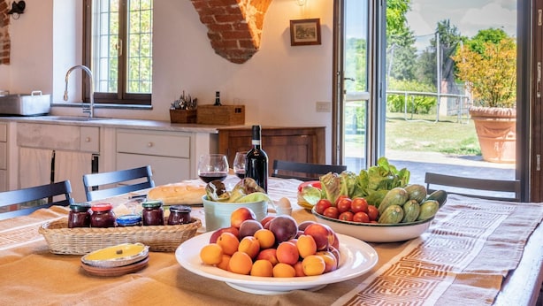 A kitchen with a rustic brick ceiling, a large window with a view of greenery, and a dining table set with fruits and condiments. - Stunning private villa for 14 guests with private pool, A/C, WIFI, TV, patio and panoramic view (Soglio)